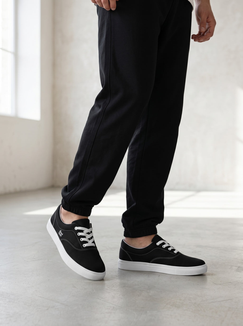 BeachBodyz® black canvas low-top sneakers with white laces and soles, featuring subtle side logo.